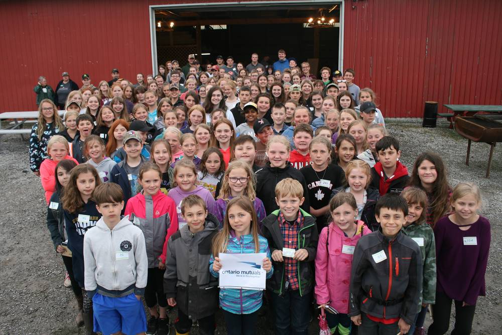 Large group of youth standing in front of barn smiling
