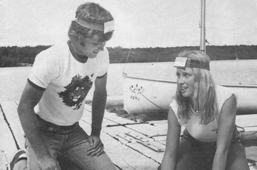 Two people on a dock completing teambuilding activity at a 4-H camp in the 1970s.