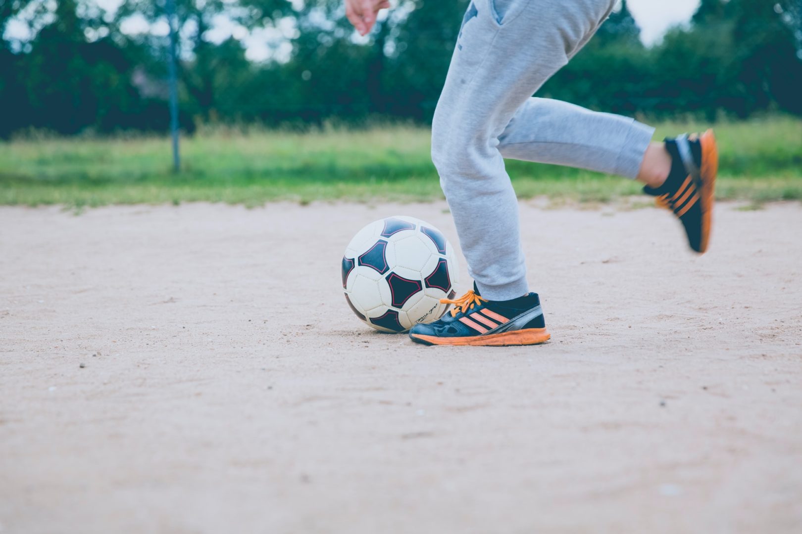 kid kicking a soccer ball on asphalt