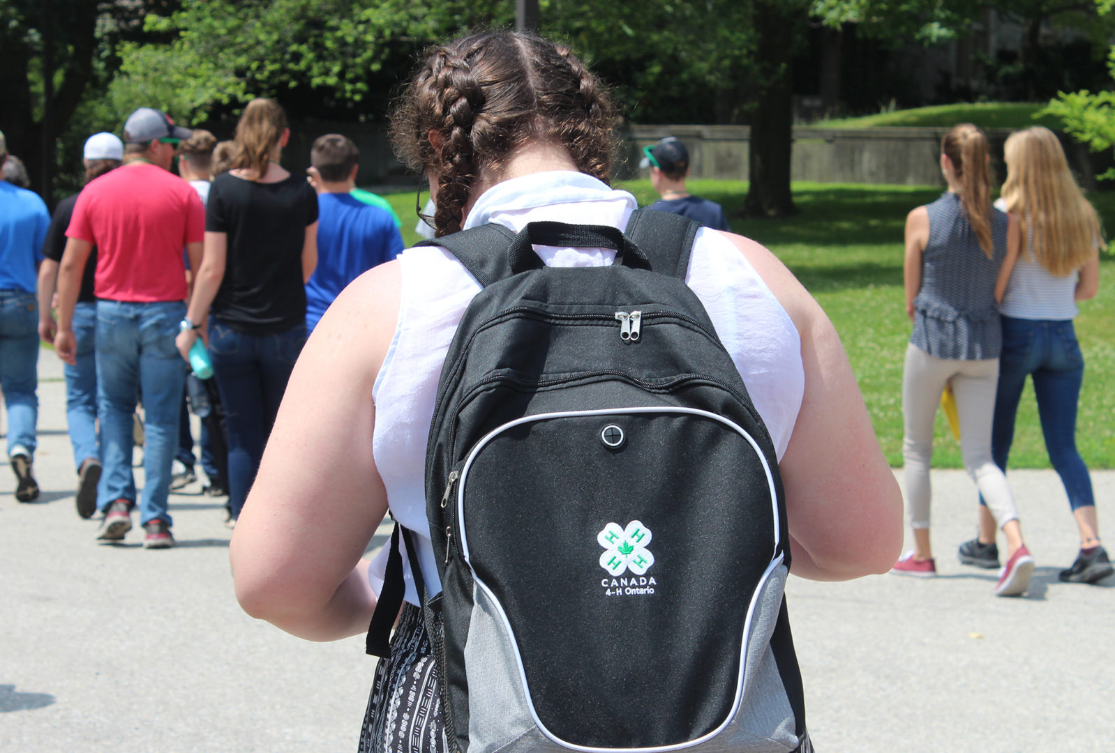 Youth walking away in group wearing 4-H back pack on sunny day