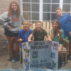 Members at the poultry club meeting with their 4-H display board