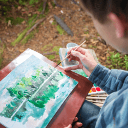 boy painting a woods scene